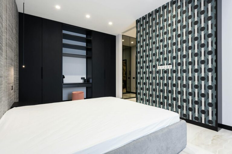 Elegant modern bedroom featuring geometric wallpaper, sleek furnishings, and minimalist design.