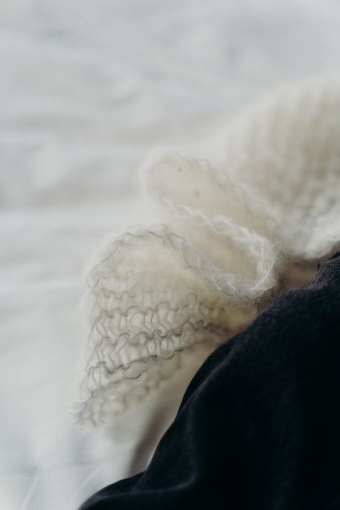 A close-up shot of delicate white knitted wool on a black surface, showcasing texture.